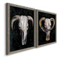 Angled view of a set of two gray barnwood framed canvas prints featuring two dramatic Western animal paintings featuring ram and cattle skulls against black grounds.