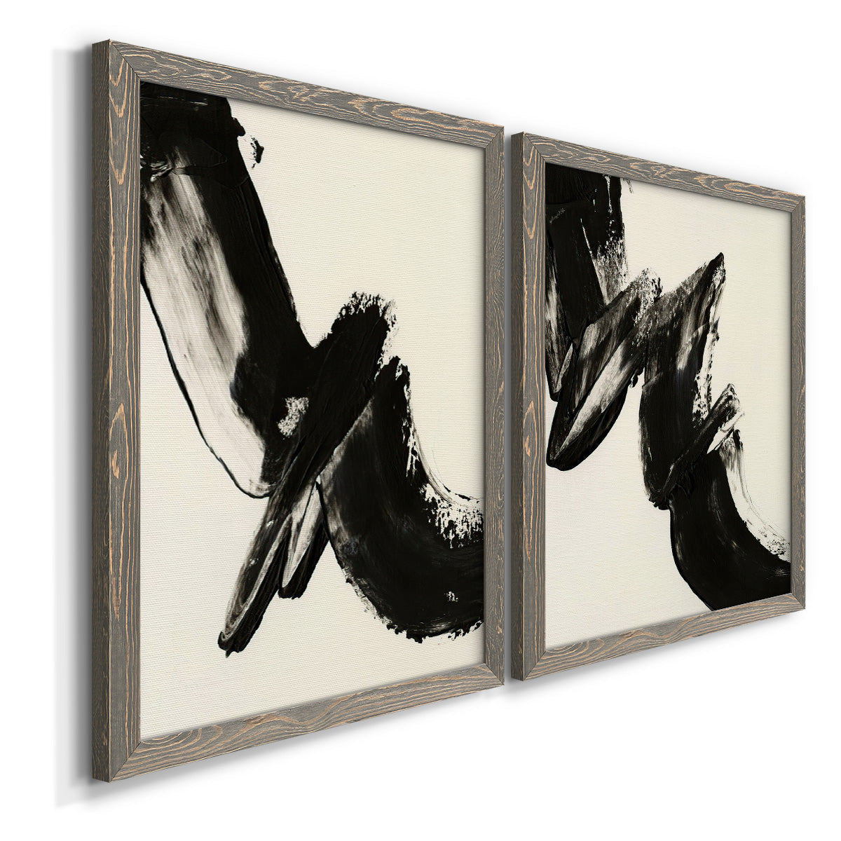 Angled view of a set of two gray barnwood framed canvas prints featuring two bold gestural abstracts featuring sweeping black calligraphic brushstrokes.