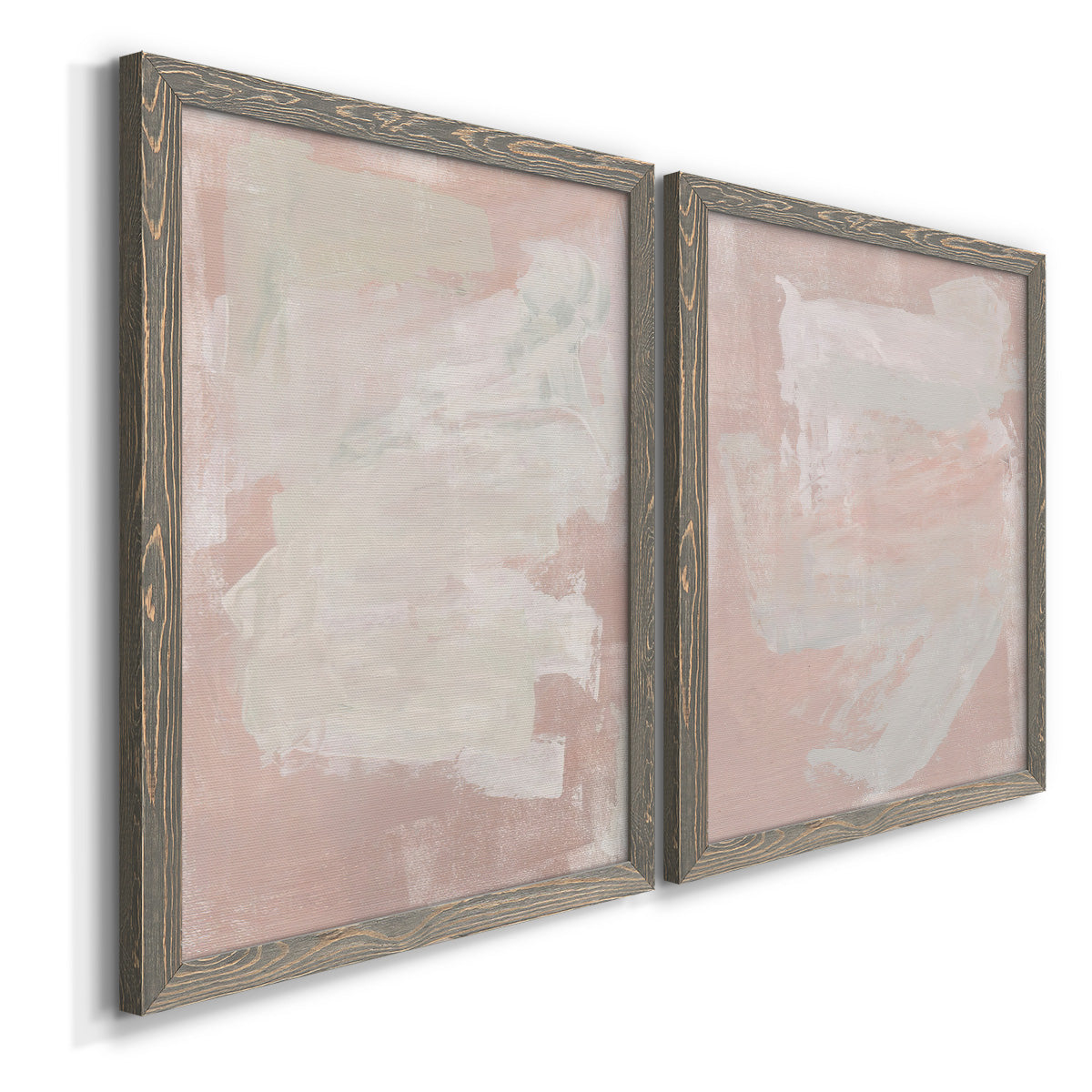 Angled view of a set of two gray barnwood framed canvas prints featuring two minimalist color-field abstracts featuring soft blush and white painterly fields.