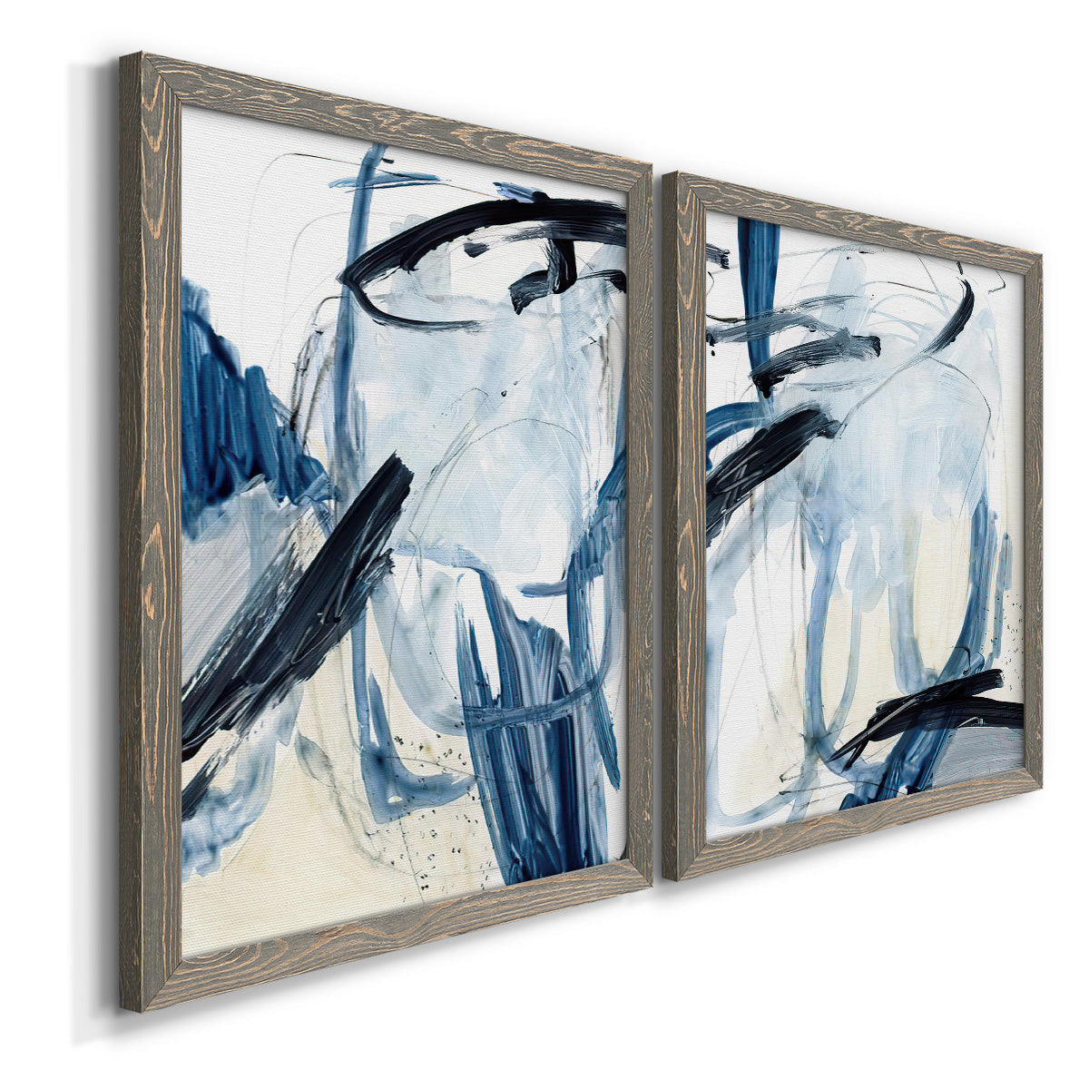 Angled view of a set of two gray barnwood framed canvas prints featuring two expressive blue abstracts featuring sweeping indigo and black gestural brushwork.