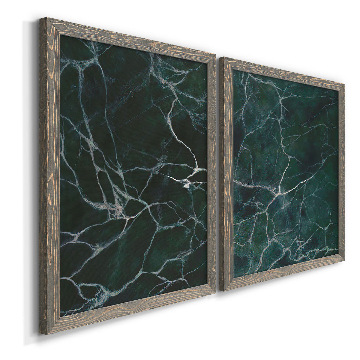 Angled view of a set of two gray barnwood framed canvas prints featuring two dramatic stone-inspired abstracts featuring dark green marble veining.