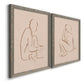 Angled view of a set of two gray barnwood framed canvas prints featuring two minimalist figurative sketches featuring seated female figures drawn with single flowing lines.