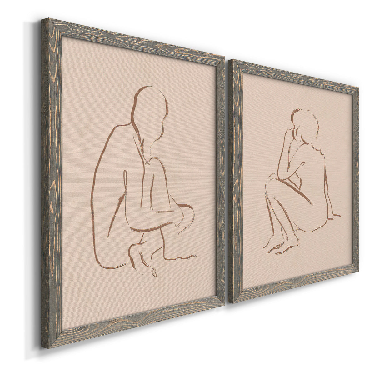 Angled view of a set of two gray barnwood framed canvas prints featuring two minimalist figurative sketches featuring seated female figures drawn with single flowing lines.