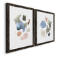 Angled view of a set of two black barnwood framed canvas prints featuring two airy minimalist abstracts featuring scattered translucent watercolor shapes.