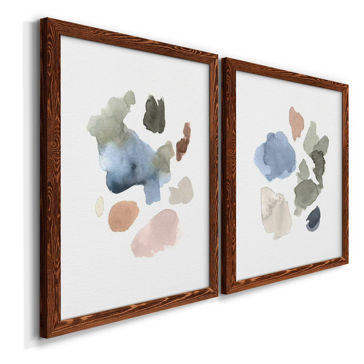 Angled view of a set of two maple barnwood framed canvas prints featuring two airy minimalist abstracts featuring scattered translucent watercolor shapes.