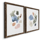 Angled view of a set of two walnut barnwood framed canvas prints featuring two airy minimalist abstracts featuring scattered translucent watercolor shapes.