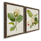 Angled view of a set of two walnut barnwood framed canvas prints featuring two traditional botanical paintings featuring white magnolia blossoms and glossy green leaves.