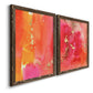 Angled view of a set of two walnut barnwood framed canvas prints featuring two glamorous fluid abstracts featuring luminous coral orange and pink color fields with gold flecks.