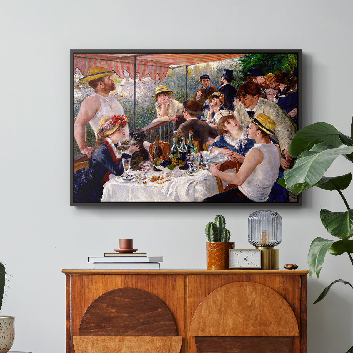 Luncheon of the Boating Party (Le Déjeuner des canotiers), 1880-1881 by Pierre-Auguste Renoir in a black floater framed canvas featuring a group of elegantly dressed people dining together on a sunlit balcony overlooking the river, displayed above a wood console cabinet.