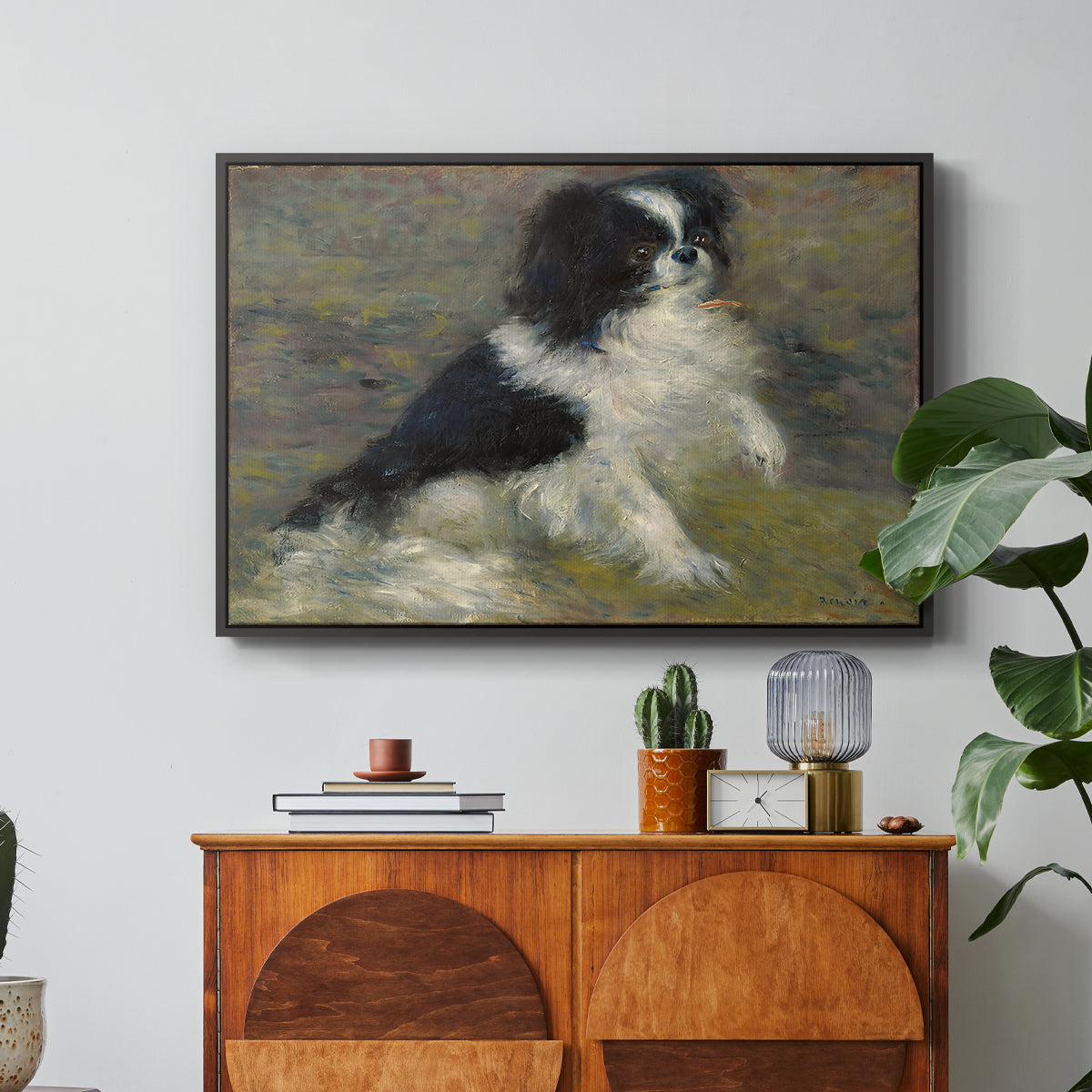 Tama, the Japanese Dog, c. 1876 by Pierre-Auguste Renoir in a black floater framed canvas featuring a small black and white dog standing in shallow water with soft brushstrokes, displayed above a wood console cabinet.