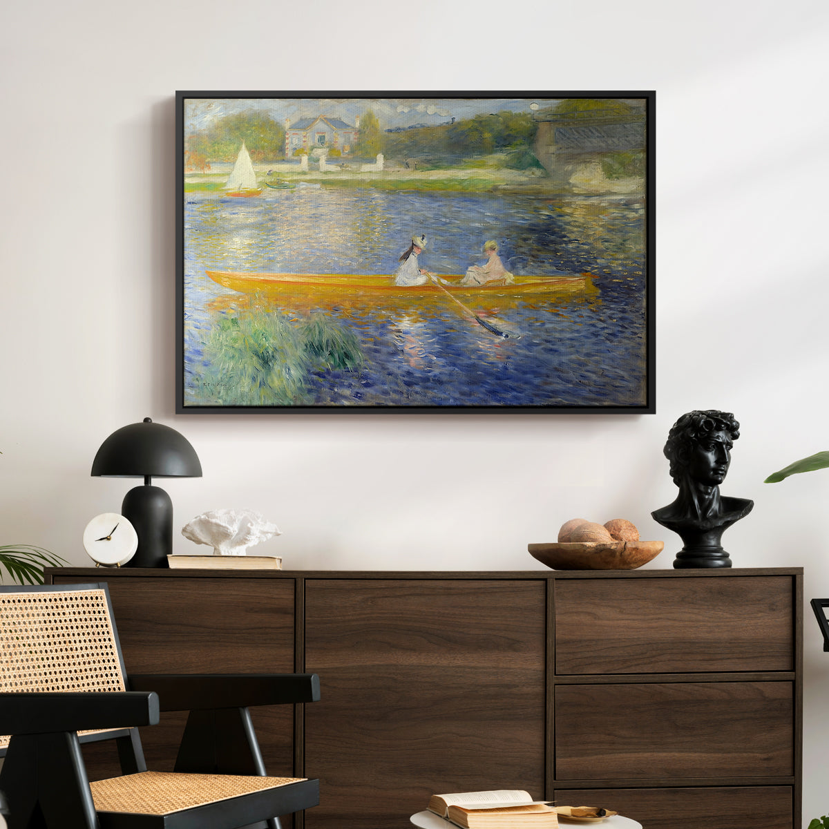 The Skiff (La Yole), 1875 by Pierre-Auguste Renoir displayed in a black floater framed canvas above a dark wood credenza in an entryway.