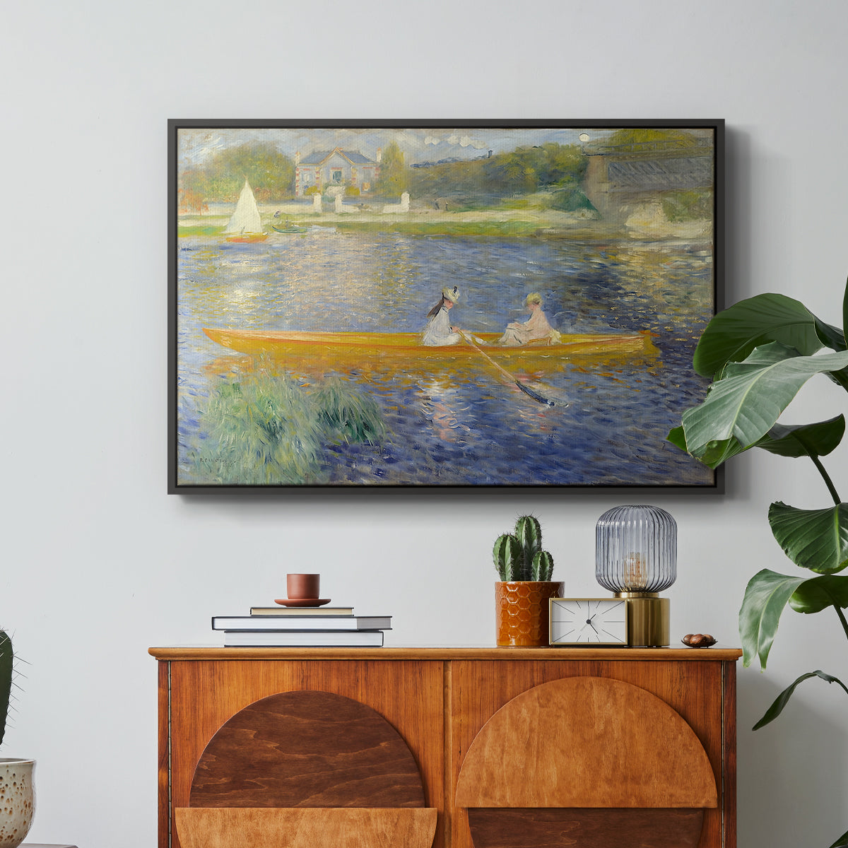 The Skiff (La Yole), 1875 by Pierre-Auguste Renoir in a black floater framed canvas featuring two figures seated in a small boat drifting across calm water, displayed above a wood console cabinet.