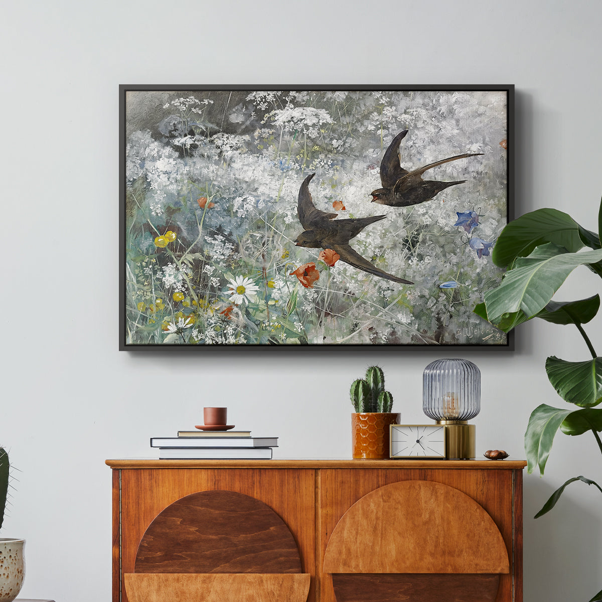 Common Swifts, 1886 by Bruno Liljefors in a black floater framed canvas featuring a flock of birds in flight soaring across open sky above landscape, displayed above a wood console cabinet.