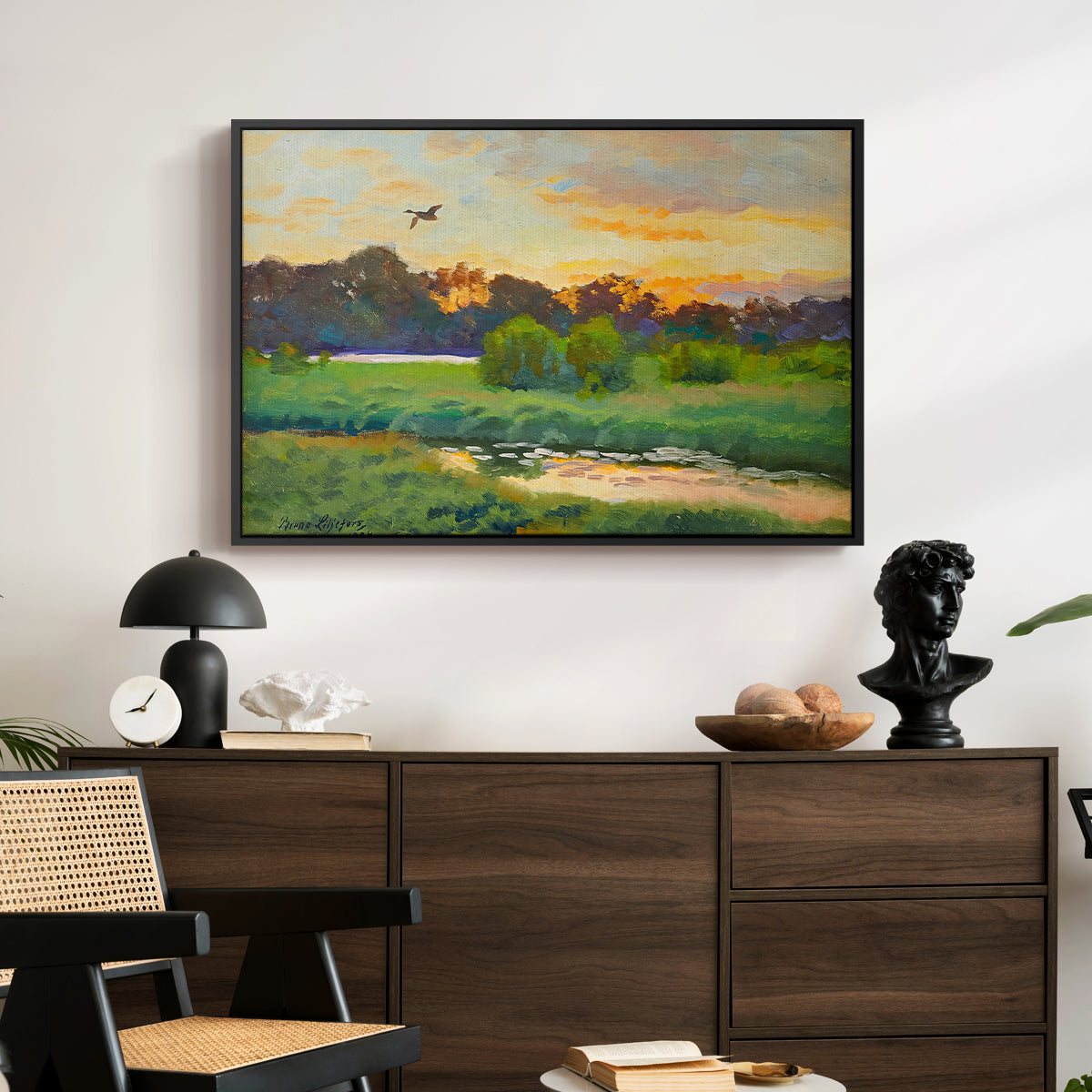 Flying Duck at Sunset, 1924 by Bruno Liljefors displayed in a black floater framed canvas above a dark wood credenza in an entryway.