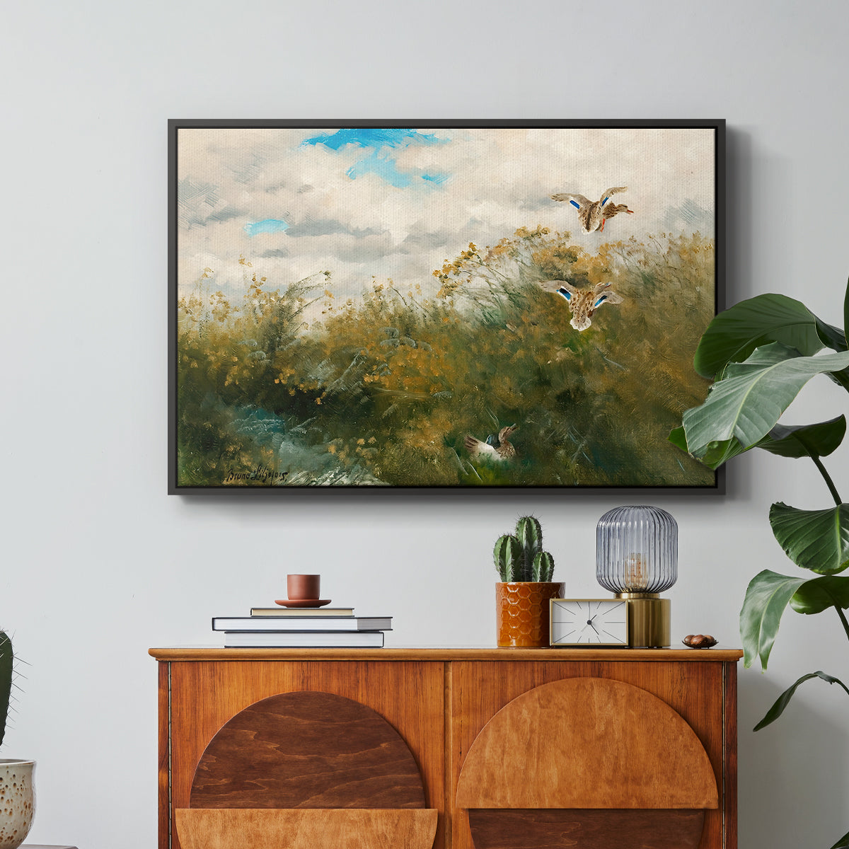Wild Ducks (Grasänder), 1890 by Bruno Liljefors in a black floater framed canvas featuring ducks moving through grassy wetland near water's edge, displayed above a wood console cabinet.