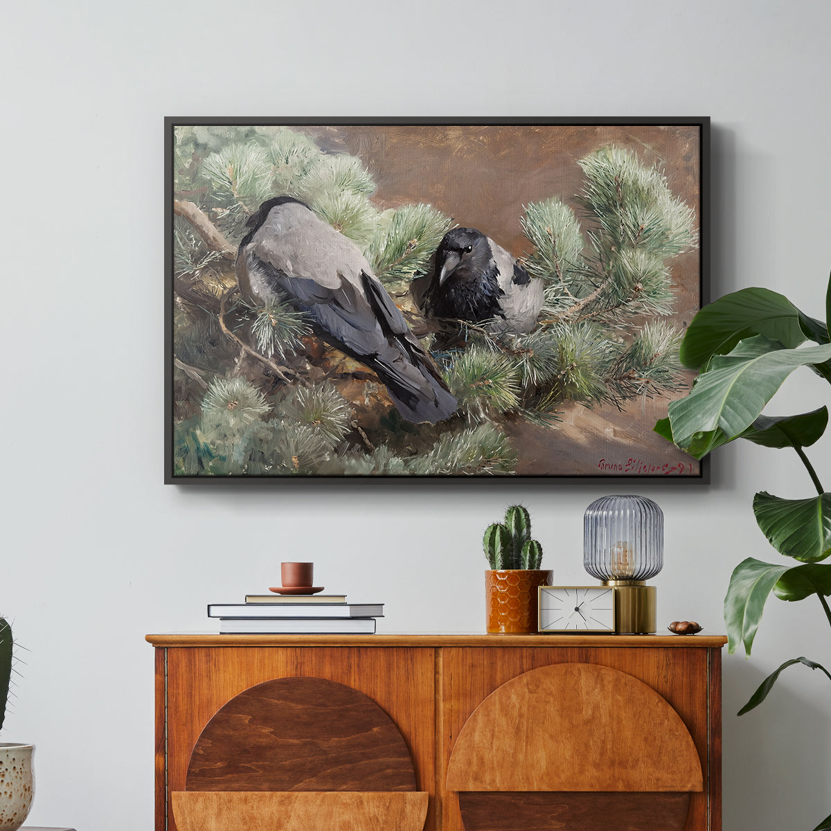 Hooded Crows (Kråkor), 1891 by Bruno Liljefors in a black floater framed canvas featuring two crows perched on ground among grass and earth tones, displayed above a wood console cabinet.