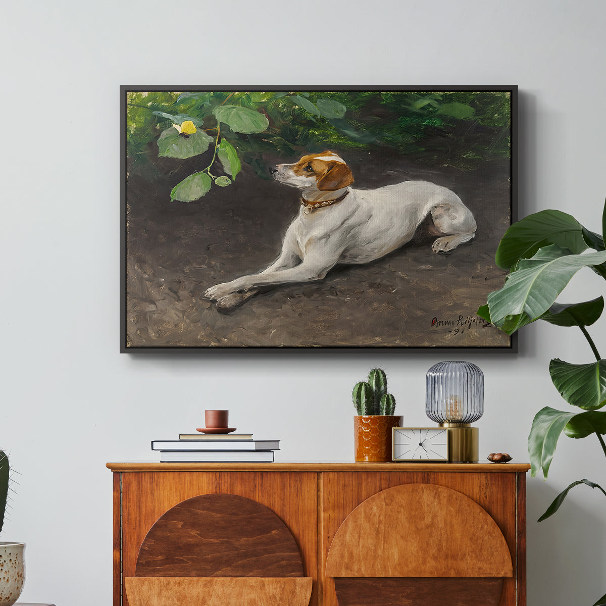 Portrait of a Dog, 1891 by Bruno Liljefors in a black floater framed canvas featuring a dog lying on ground with head raised in natural outdoor setting, displayed above a wood console cabinet.