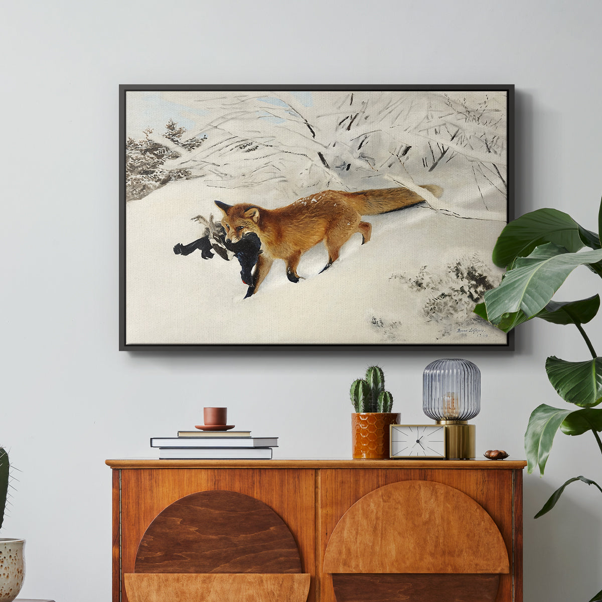 Fox in Snow Landscape, 1900 by Bruno Liljefors in a black floater framed canvas featuring a fox running across snowy landscape with sparse vegetation, displayed above a wood console cabinet.