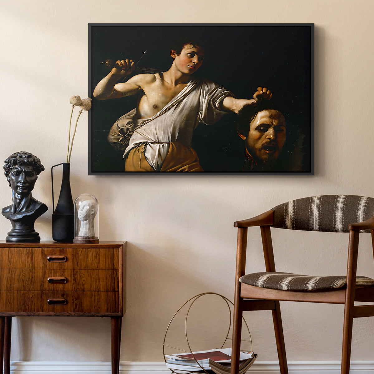 David with the Head of Goliath (Vienna Version), c. 1607 by Caravaggio as a black floater framed canvas featuring a Baroque depiction of youth holding severed head in shadowy setting, styled above a mid-century console in a contemporary living area.