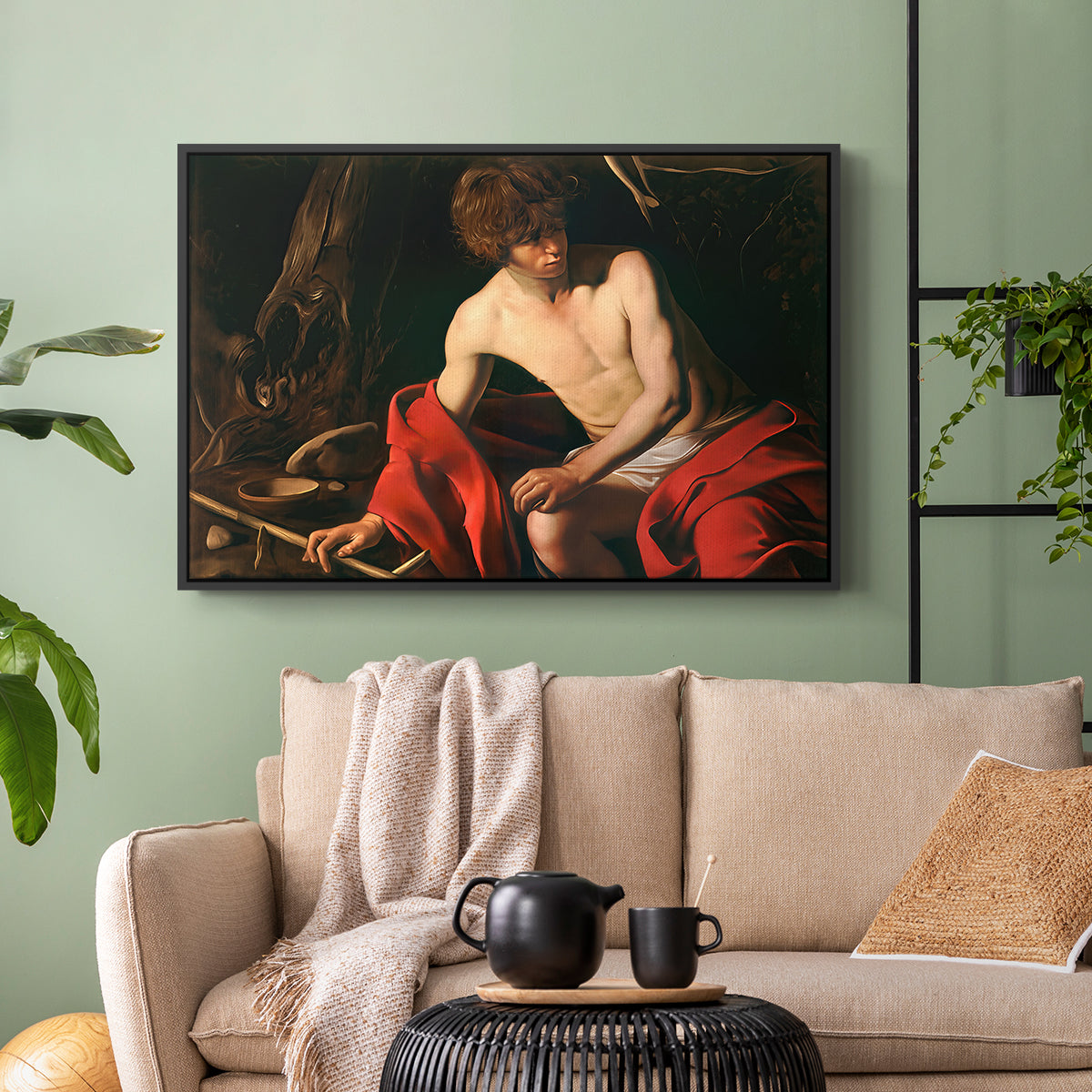 Black floater framed canvas featuring a contemplative religious figure in rustic wilderness environment, displayed above a sofa in a modern living room.
