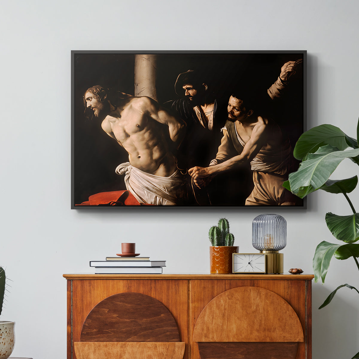 The Flagellation of Christ at the Column (Rouen Version), 1606 by Caravaggio in a black floater framed canvas featuring Christ bound to column while being whipped by surrounding figures, displayed above a wood console cabinet.