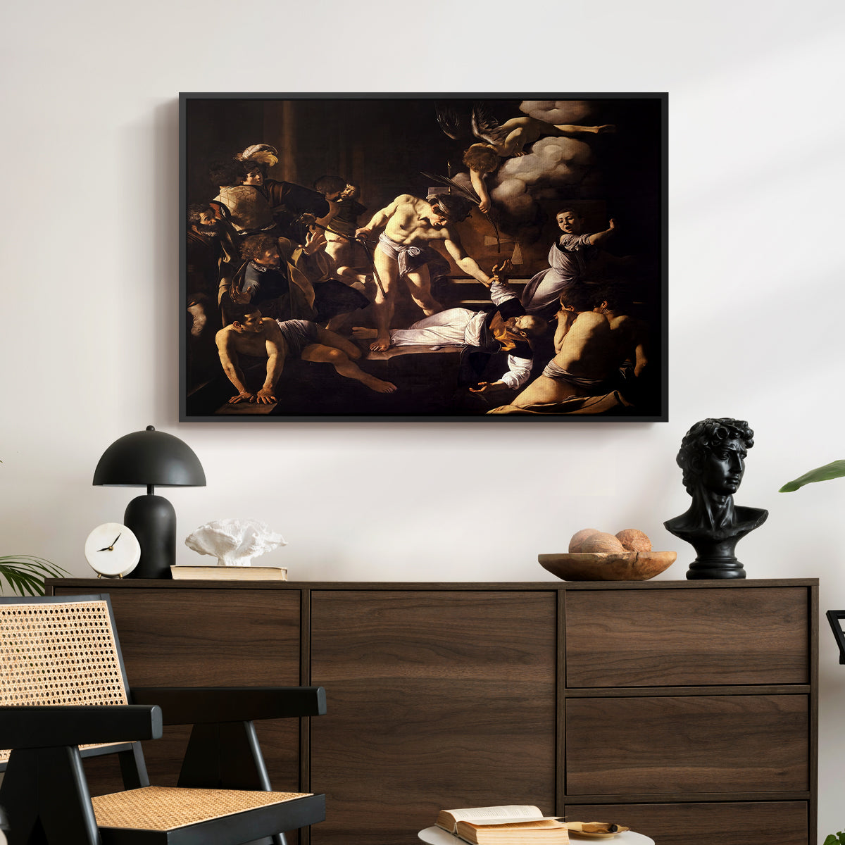 The Martyrdom of Saint Matthew, 1599-1600 by Caravaggio displayed in a black floater framed canvas above a dark wood credenza in an entryway.