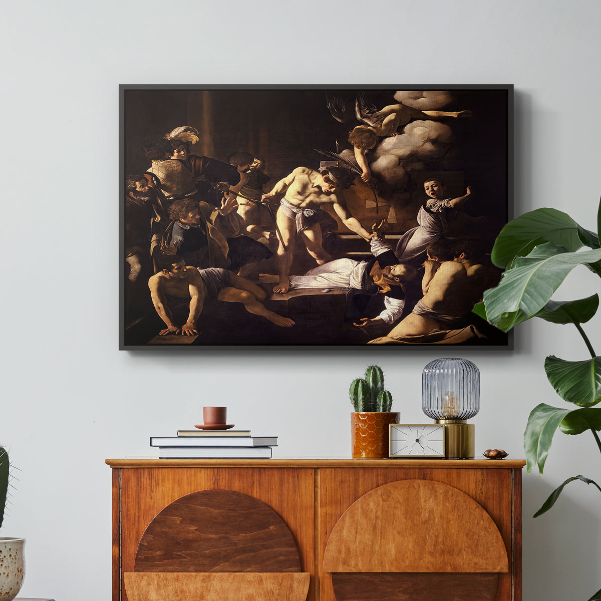 The Martyrdom of Saint Matthew, 1599-1600 by Caravaggio in a black floater framed canvas featuring a chaotic scene of Saint Matthew being attacked by executioner in church, displayed above a wood console cabinet.
