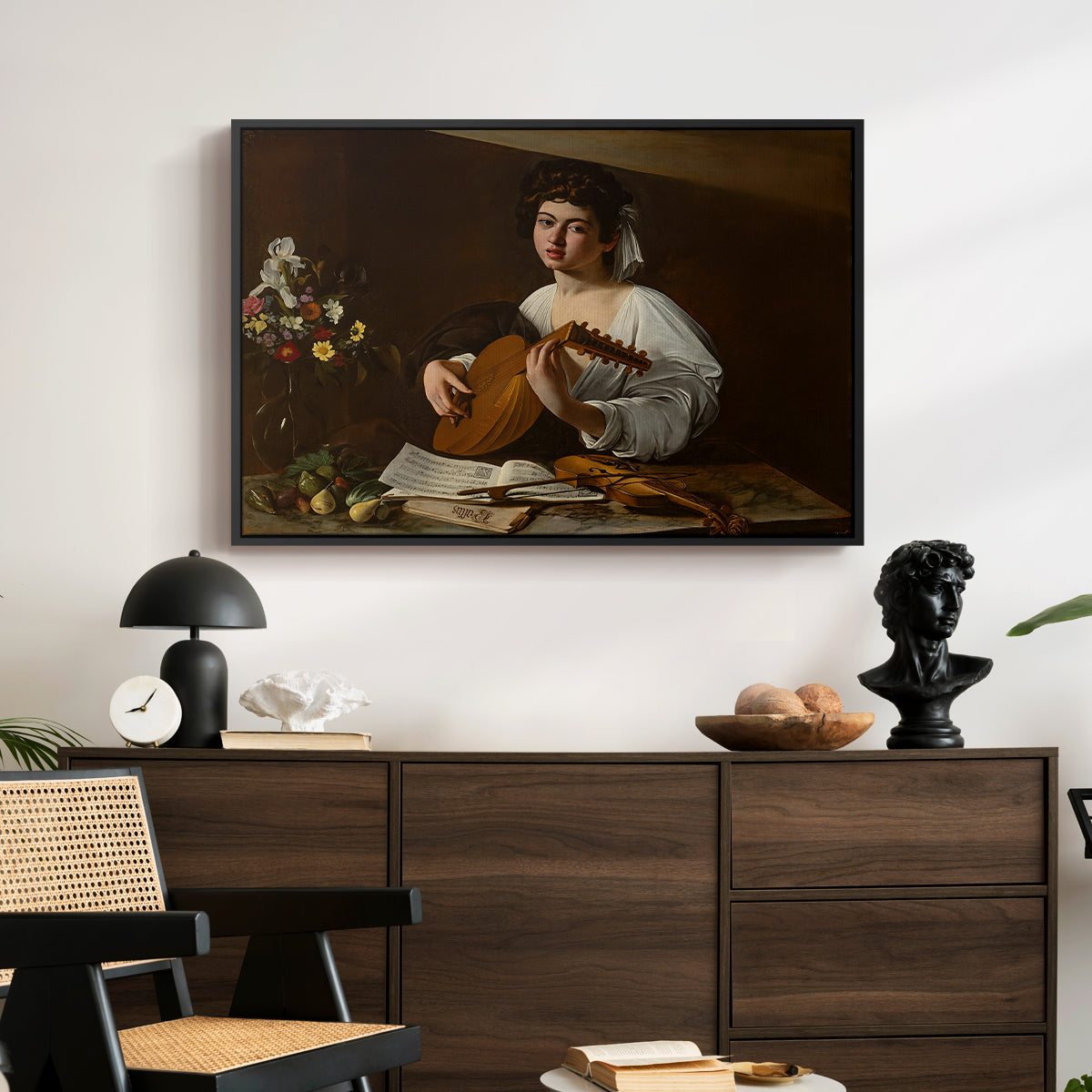 The Lute Player (Hermitage Version), c. 1596 by Caravaggio displayed in a black floater framed canvas above a dark wood credenza in an entryway.