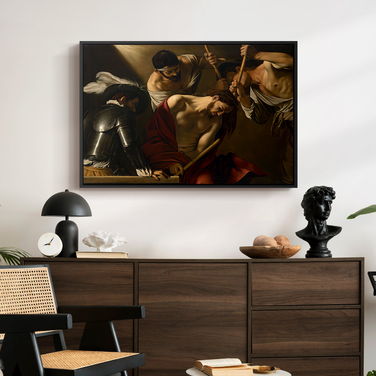 The Crowning with Thorns (Vienna Version), c. 1602-1604 by Caravaggio displayed in a black floater framed canvas above a dark wood credenza in an entryway.