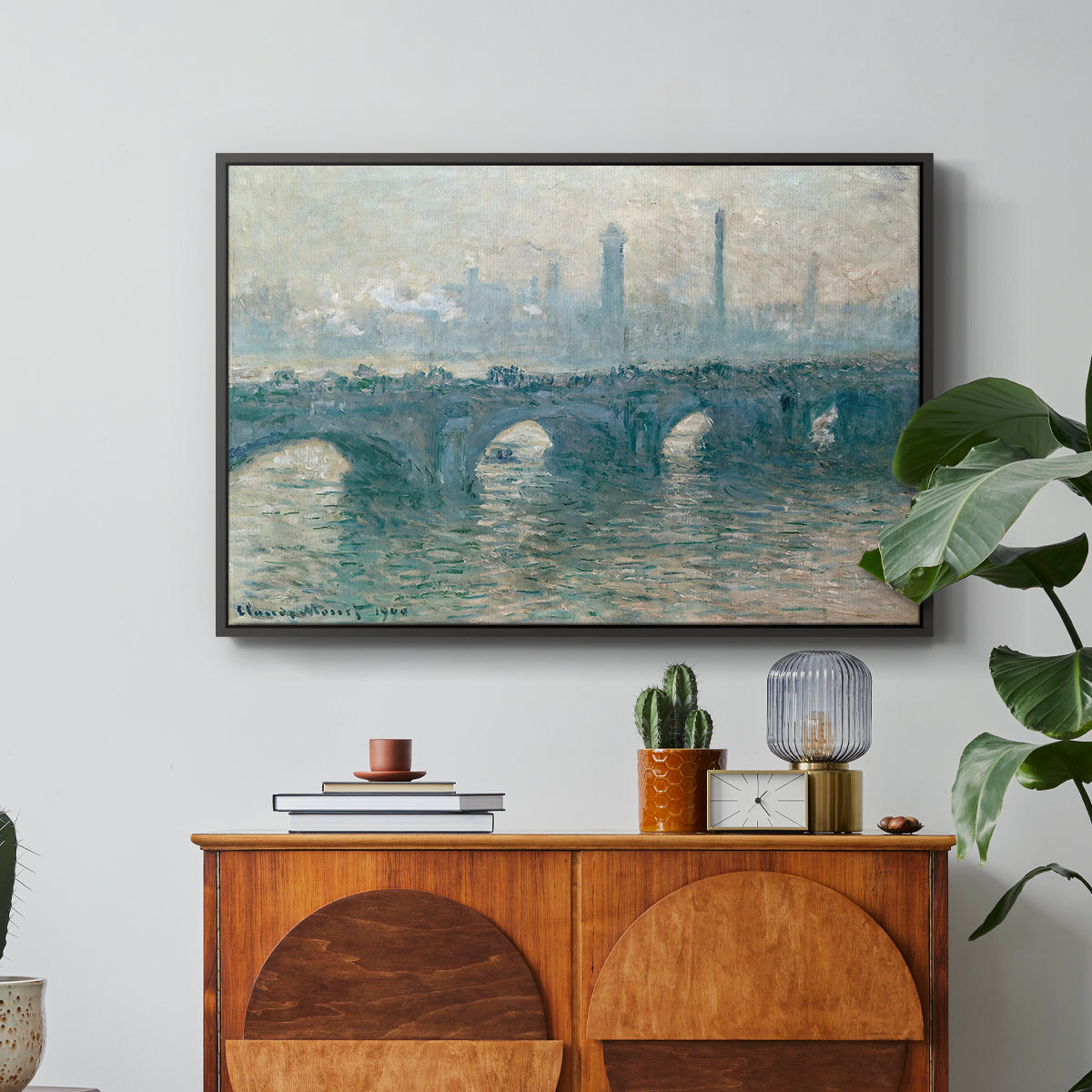 Waterloo Bridge, Gray Weather, 1900 by Claude Monet in a black floater framed canvas featuring a hazy view of Waterloo Bridge over river in gray atmospheric light, displayed above a wood console cabinet.