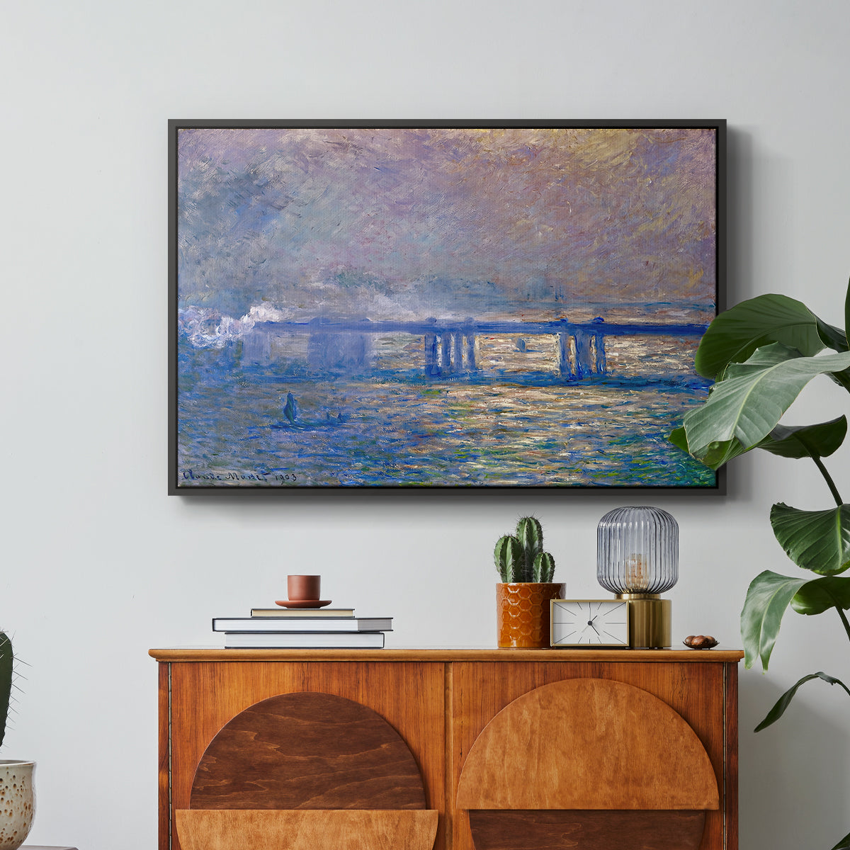 Charing Cross Bridge, 1903 by Claude Monet in a black floater framed canvas featuring an impressionist view of bridge stretching across river with soft light and haze, displayed above a wood console cabinet.