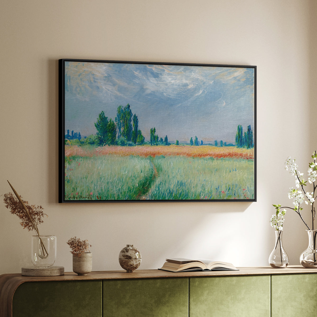 Black floater framed canvas of The Wheat Field (Champ de Blé), 1881 by Claude Monet, featuring an impressionist depiction of ripened grain field in countryside above a sideboard in a softly lit hallway.
