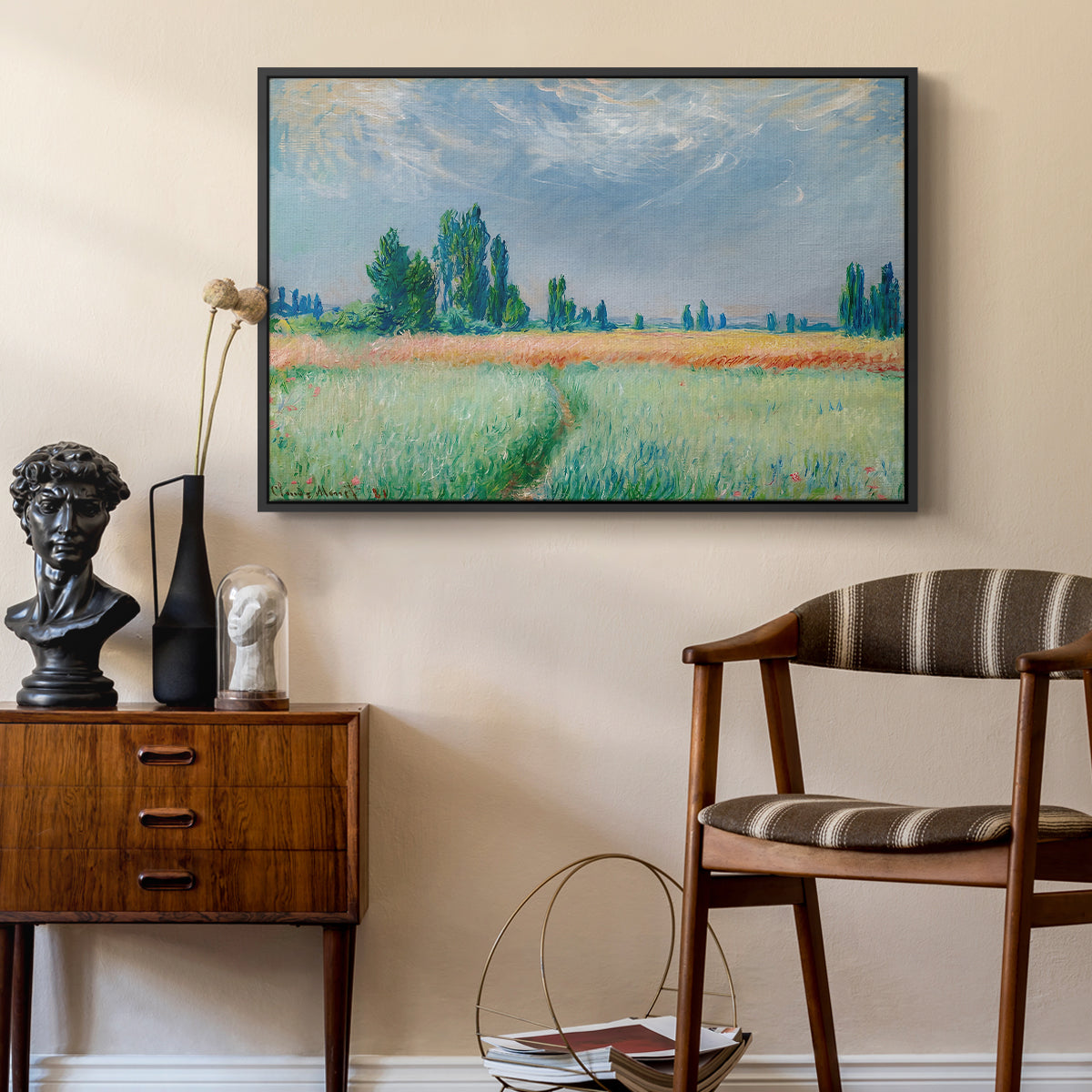 The Wheat Field (Champ de Blé), 1881 by Claude Monet as a black floater framed canvas featuring an agricultural landscape with tall wheat and distant horizon, styled above a mid-century console in a contemporary living area.