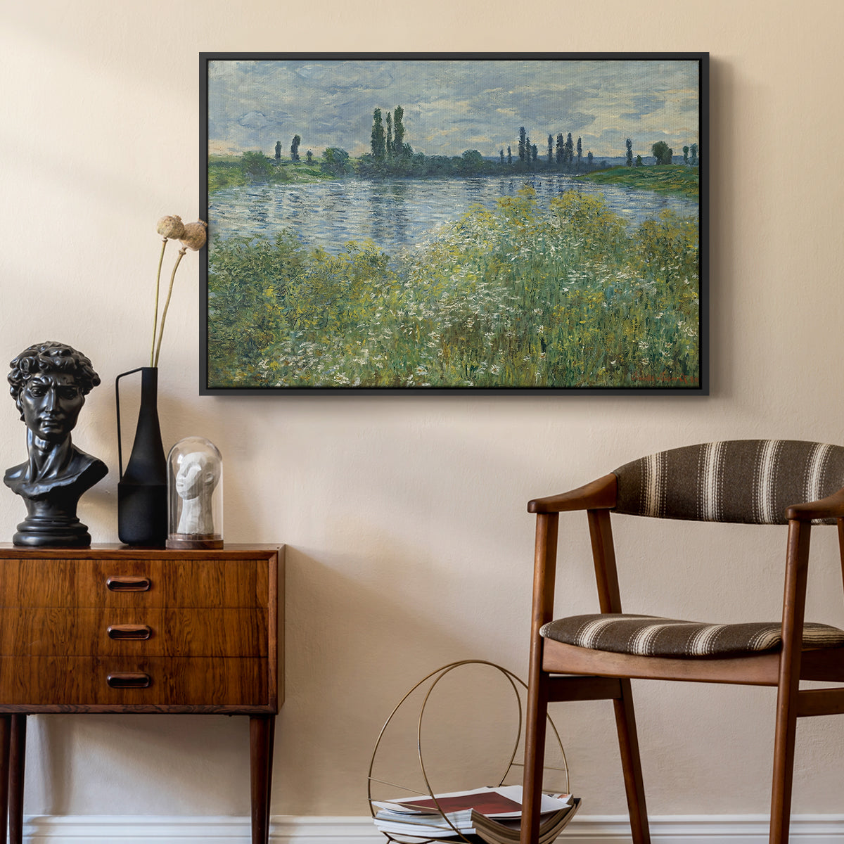 Banks of the Seine, Vétheuil, 1880 by Claude Monet as a black floater framed canvas featuring a tranquil riverside scene with houses and vegetation, styled above a mid-century console in a contemporary living area.