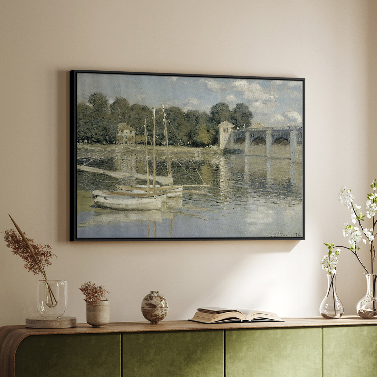 Black floater framed canvas of The Bridge at Argenteuil, 1874 by Claude Monet, featuring an impressionist river scene with boats passing beneath bridge above a sideboard in a softly lit hallway.