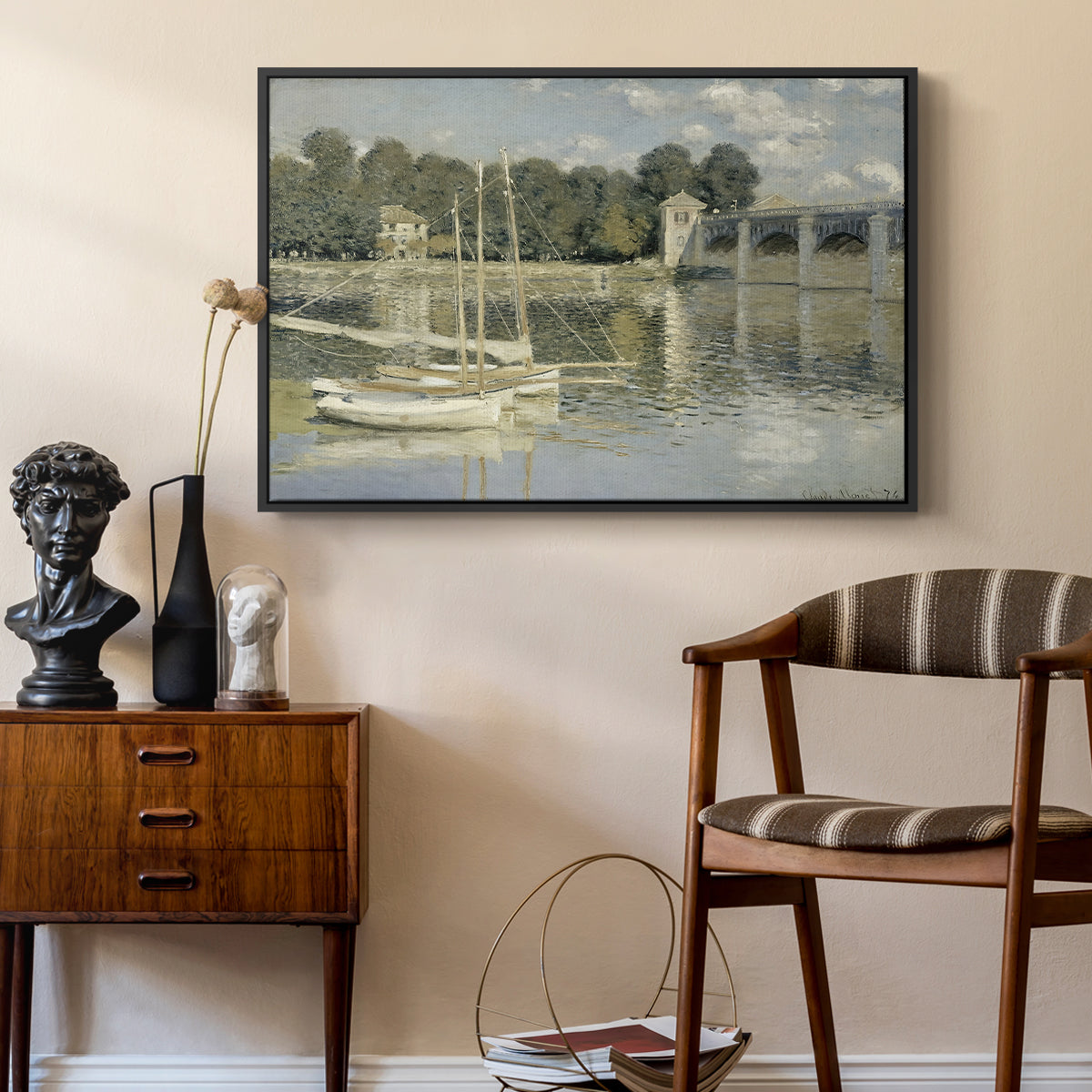 The Bridge at Argenteuil, 1874 by Claude Monet as a black floater framed canvas featuring a bright landscape featuring bridge and sailboats on calm water, styled above a mid-century console in a contemporary living area.