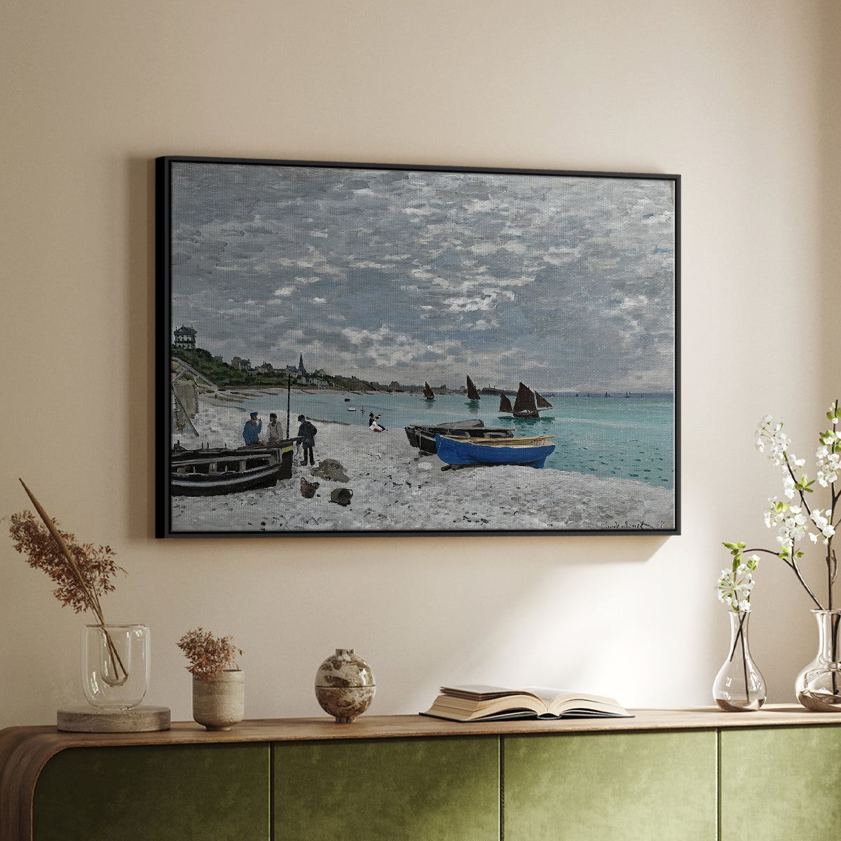 Black floater framed canvas of The Beach at Sainte-Adresse, 1867 by Claude Monet, featuring a lively beach scene with people overlooking water and ships above a sideboard in a softly lit hallway.