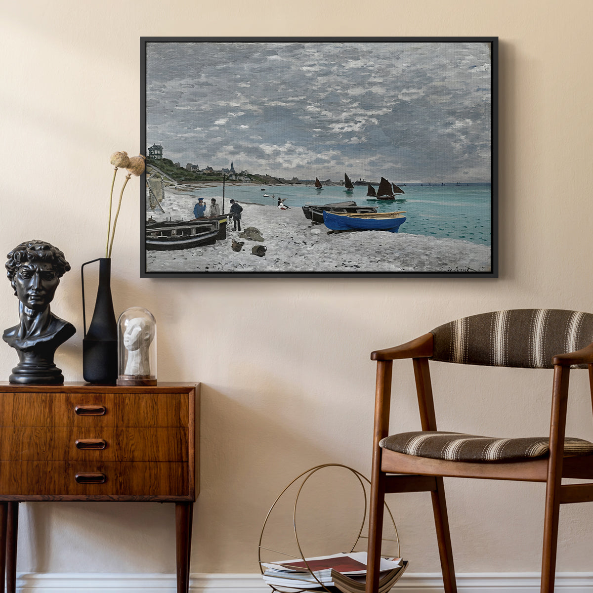 The Beach at Sainte-Adresse, 1867 by Claude Monet as a black floater framed canvas featuring a coastal landscape with sailboats and visitors on cliffside, styled above a mid-century console in a contemporary living area.