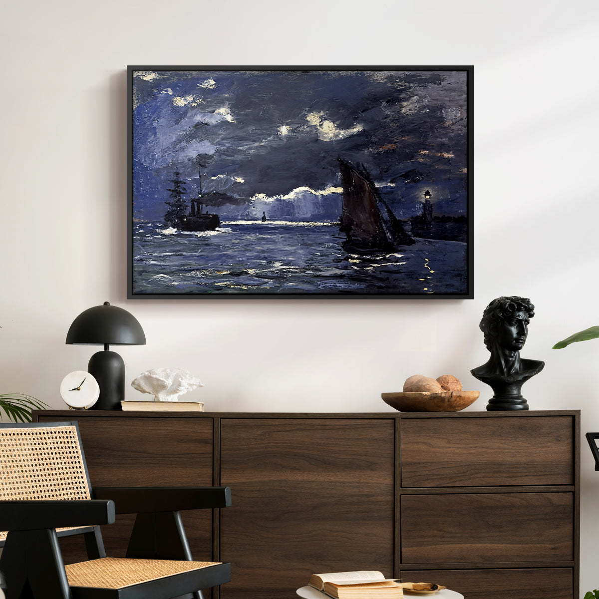 A Seascape, Shipping by Moonlight, 1864 by Claude Monet displayed in a black floater framed canvas above a dark wood credenza in an entryway.