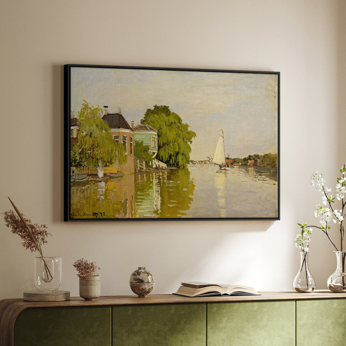 Black floater framed canvas of Houses on the Achterzaan, 1871 by Claude Monet, featuring riverside homes with trees and mirrored reflections in water above a sideboard in a softly lit hallway.
