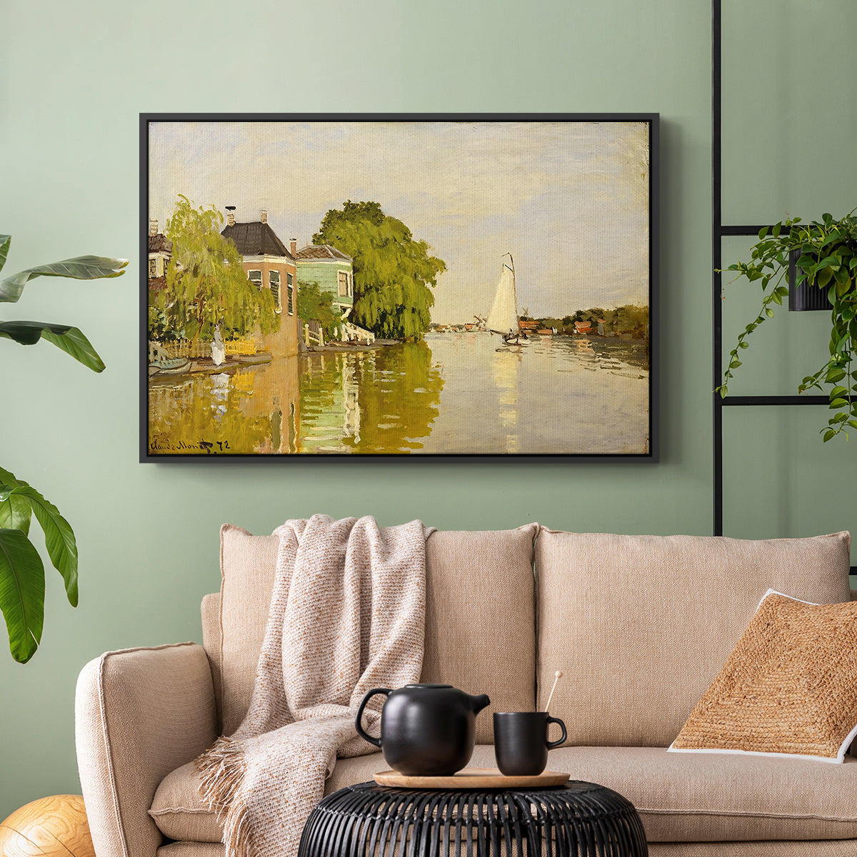 Black floater framed canvas featuring a peaceful village scene with houses bordering water, displayed above a sofa in a modern living room.