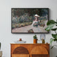 Young Girl in the Garden at Giverny, 1888 by Claude Monet in a black floater framed canvas featuring a young girl seated in lush garden surrounded by blooming flowers, displayed above a wood console cabinet.