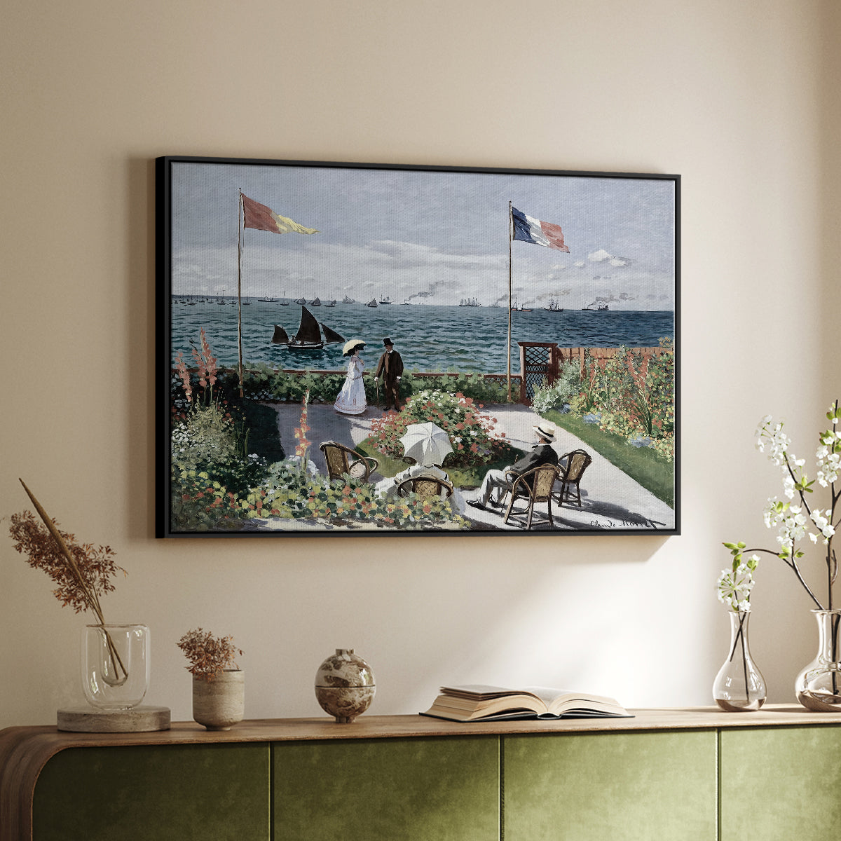 Black floater framed canvas of Garden at Sainte-Adresse, 1867 by Claude Monet, featuring an impressionist coastal garden with people and ocean view above a sideboard in a softly lit hallway.