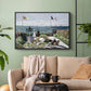 Black floater framed canvas featuring a landscaped terrace with figures and flags near shoreline, displayed above a sofa in a modern living room.