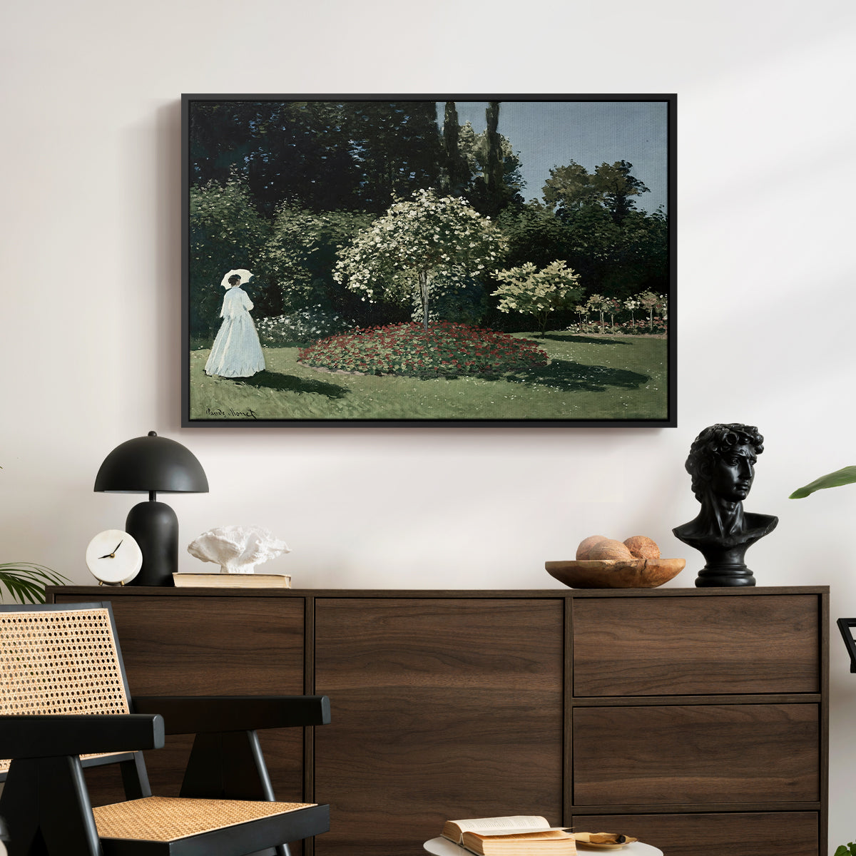Woman in the Garden, Sainte-Adresse, 1867 by Claude Monet displayed in a black floater framed canvas above a dark wood credenza in an entryway.