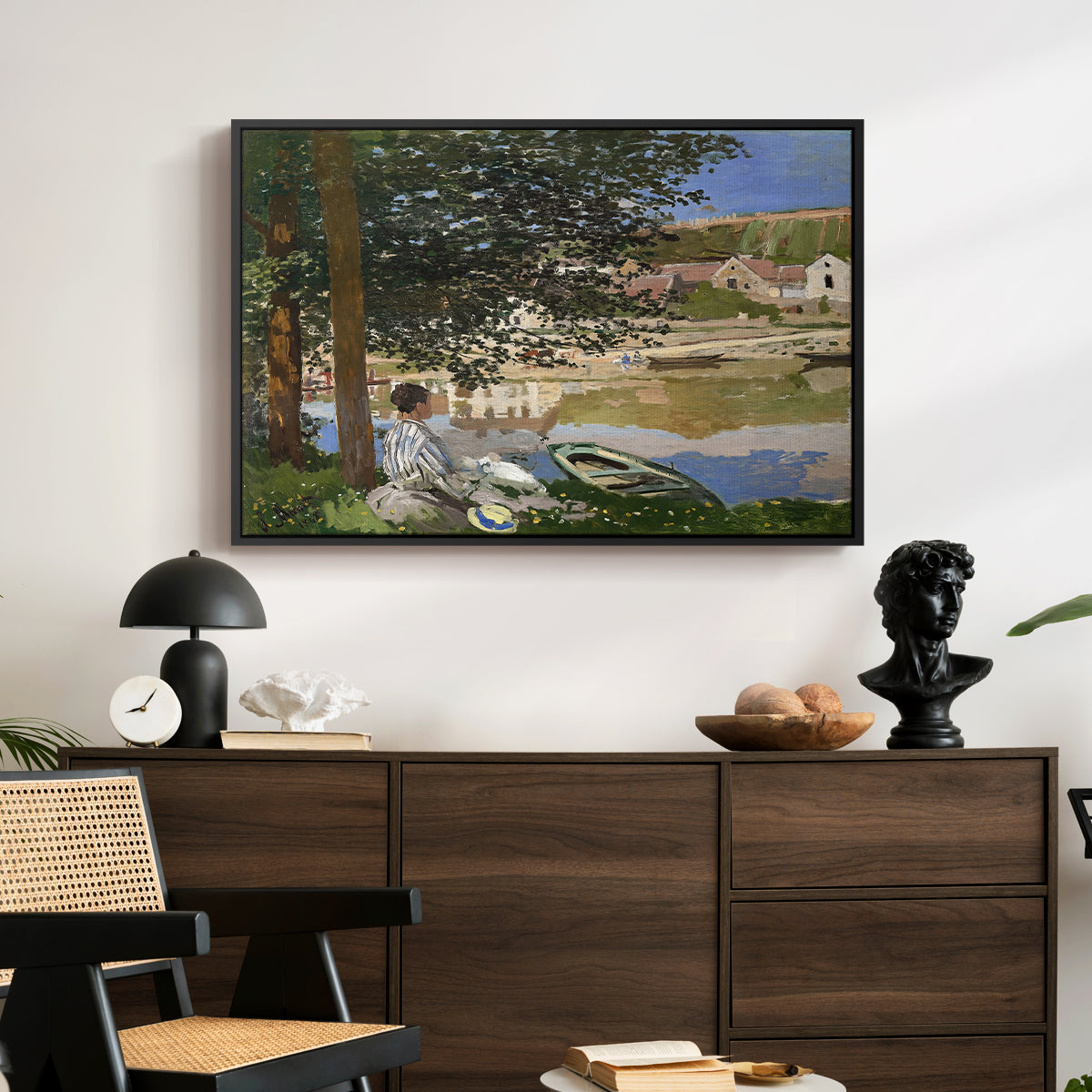 On the Bank of the Seine, Bennecourt, 1868 by Claude Monet displayed in a black floater framed canvas above a dark wood credenza in an entryway.