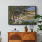 On the Bank of the Seine, Bennecourt, 1868 by Claude Monet in a black floater framed canvas featuring a woman and child seated along riverbank beneath trees in soft daylight, displayed above a wood console cabinet.