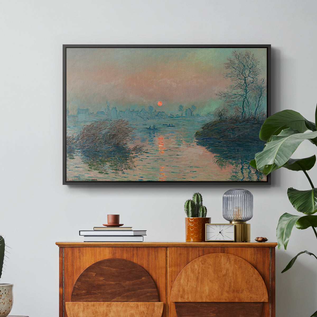 Sunset on the Seine at Lavacourt, Winter Effect, 1880 by Claude Monet in a black floater framed canvas featuring a glowing sunset over snowy river landscape with soft reflections, displayed above a wood console cabinet.