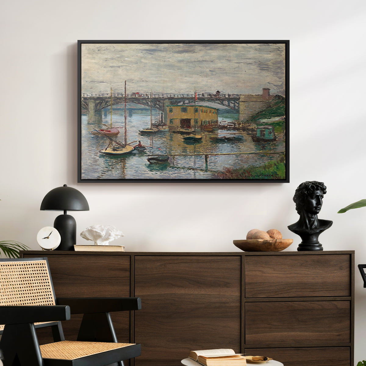 Bridge at Argenteuil on a Gray Day, c. 1876 by Claude Monet displayed in a black floater framed canvas above a dark wood credenza in an entryway.