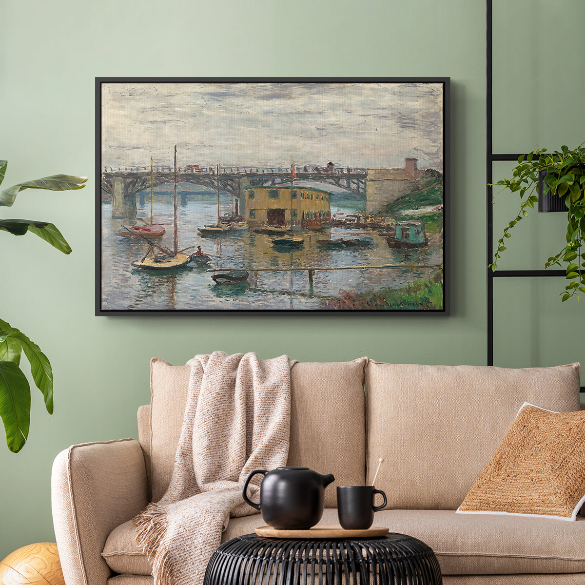 Black floater framed canvas featuring a subdued urban landscape with structure spanning river, displayed above a sofa in a modern living room.